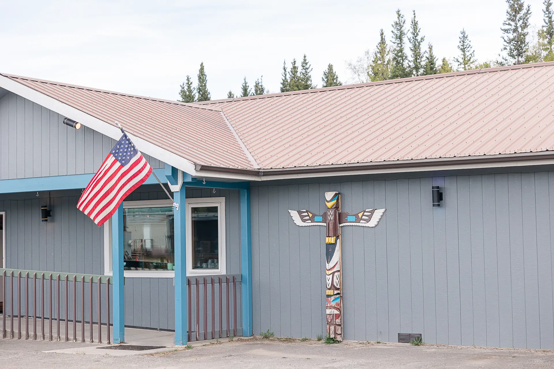 Exterior of Trophy Lodge with an American flag and carved totem by the entrance.