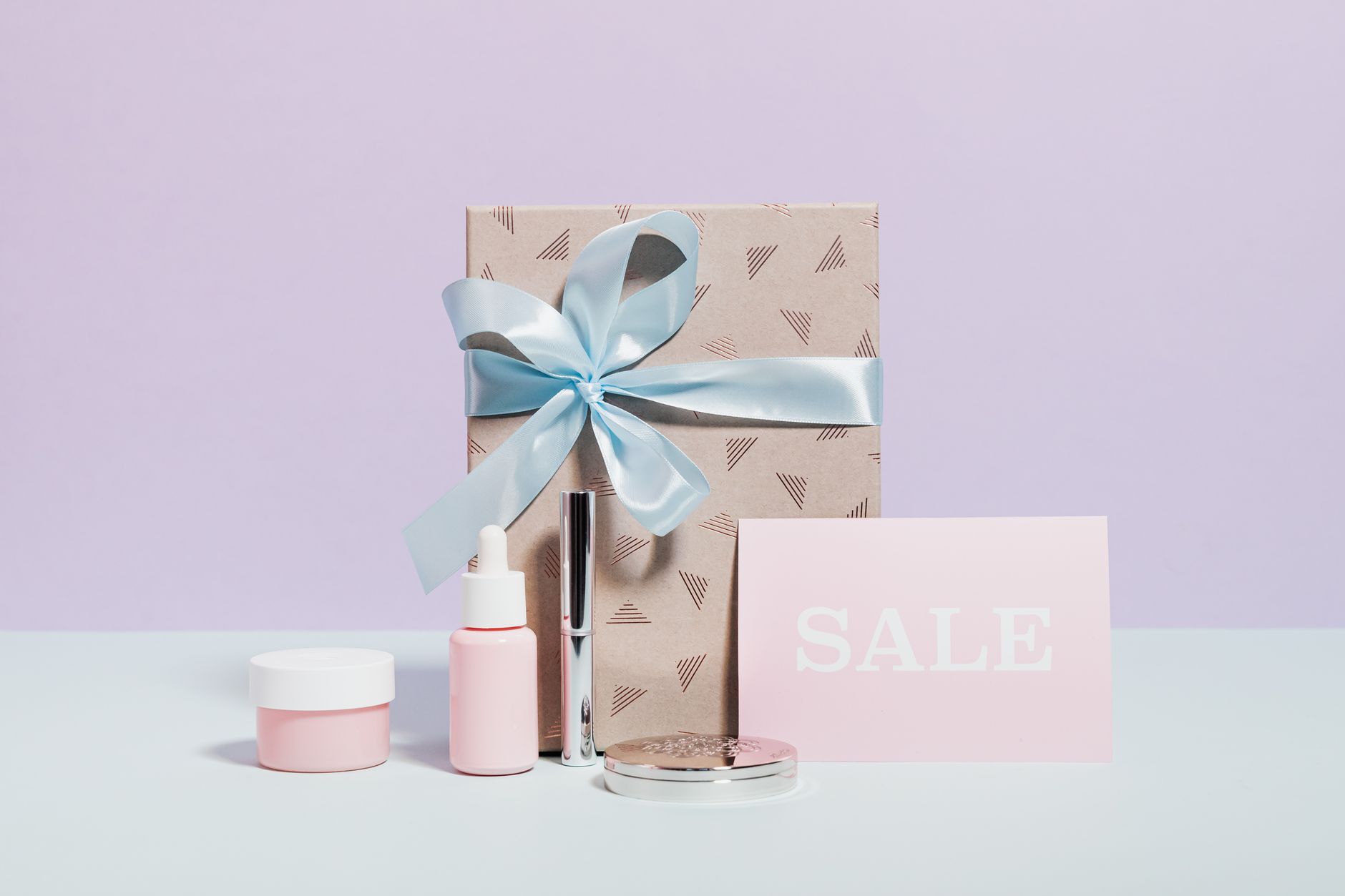 Stylish flat lay of beauty products and a gift with sale signage, perfect for promotions.