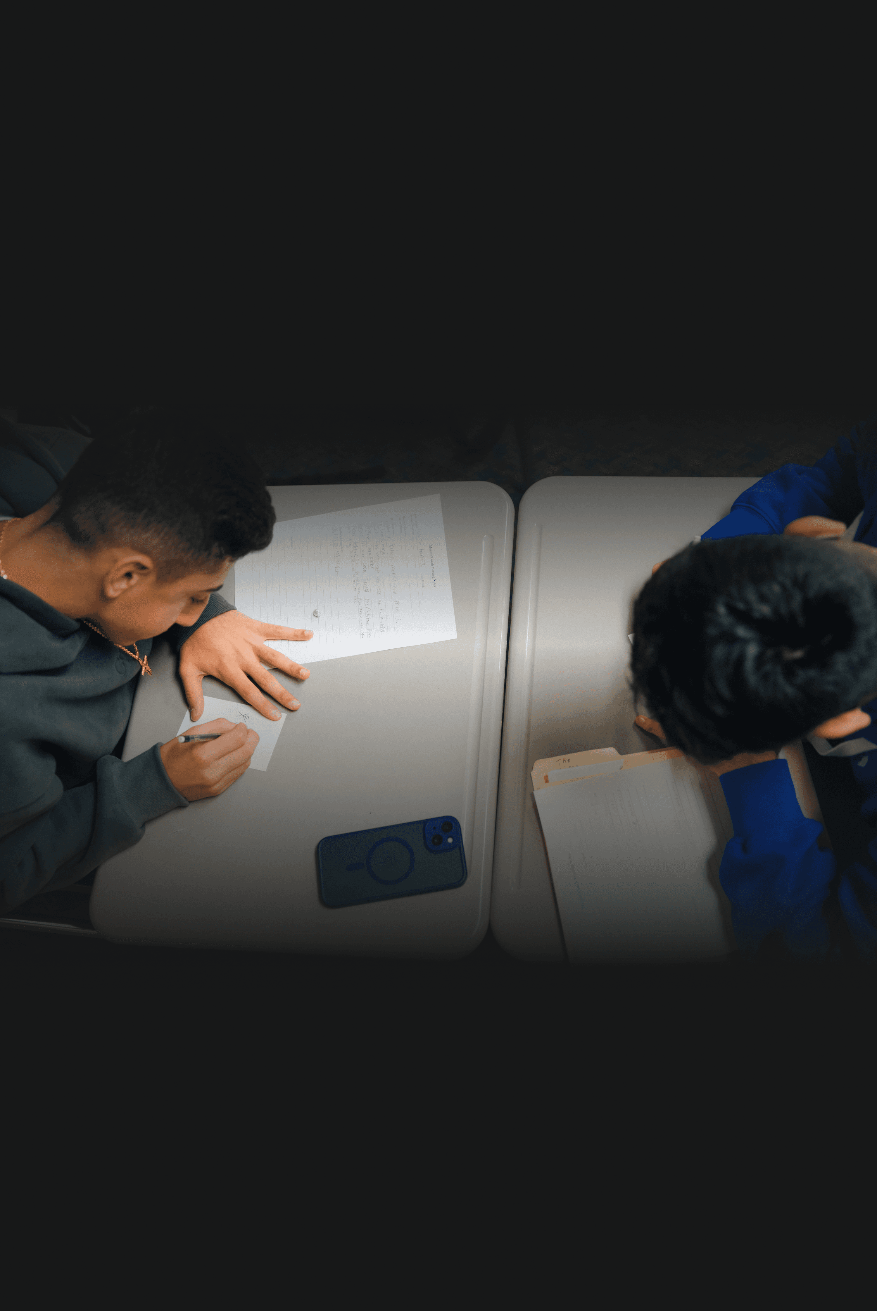 A young man in a white t-shirt stands against a light-colored background.