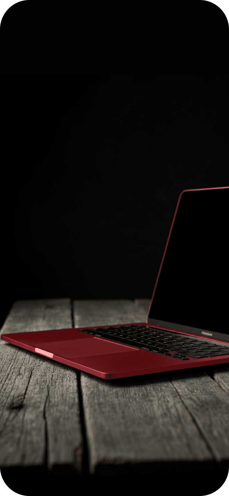 A red MacBook Pro laptop sitting on a wood table