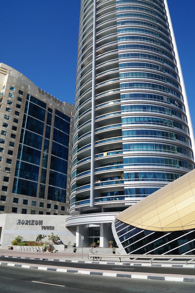 Ground level view of the Horizon Tower entrance, a prime residential building managed by expert real estate agents.