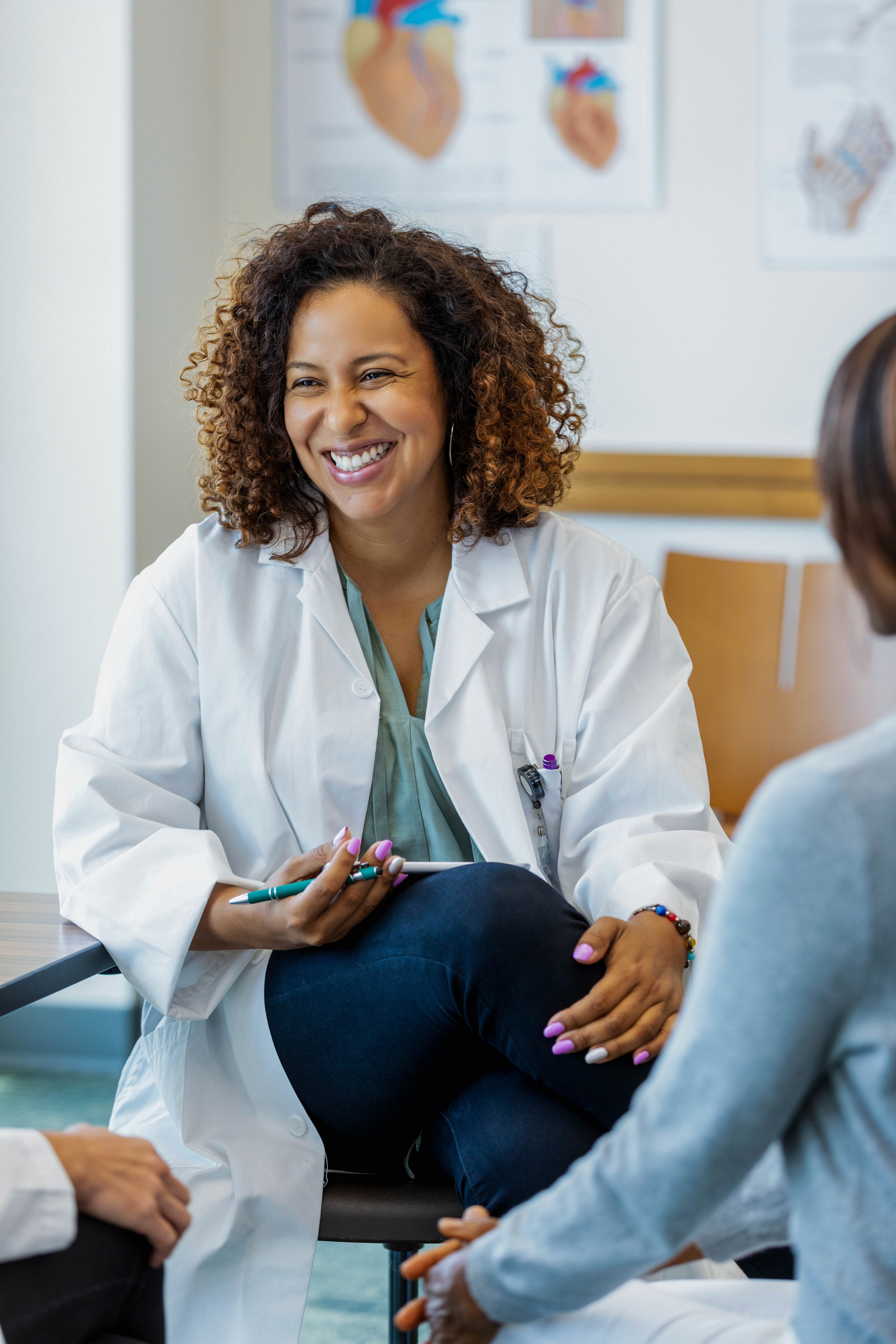A smiling woman , medical , sitting in a white coat