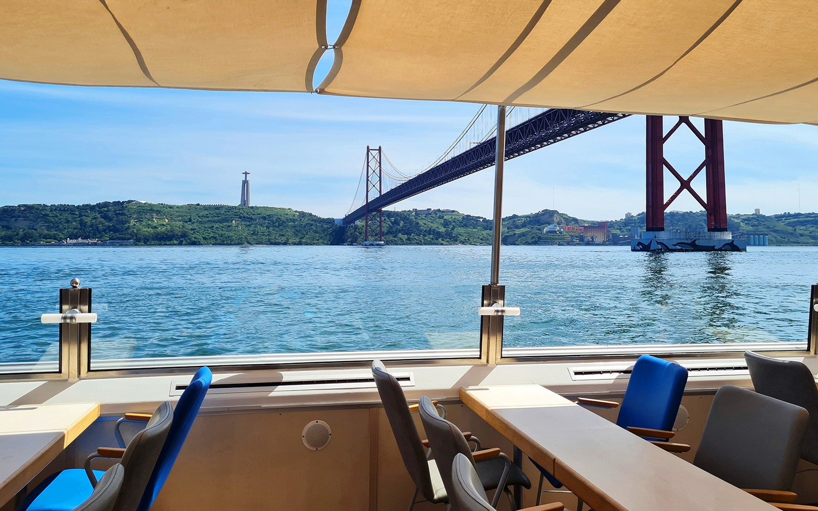 View of the 25 de Abril Bridge and Cristo Rei statue from a Tagus River cruise in Lisbon.