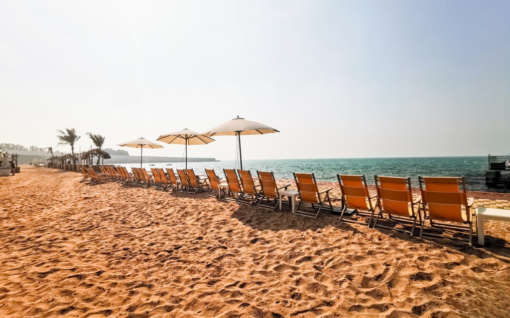 Beach chairs, umbrellas on sand, Springs 2 community: relaxation by shore.