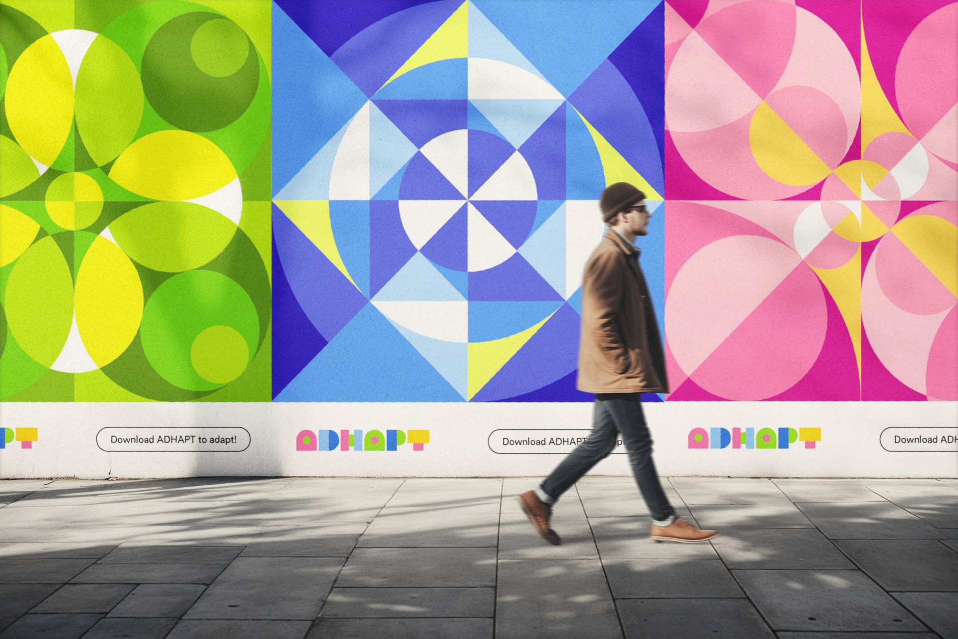 A person wearing a brown jacket, dark pants, and a dark beanie walks from left to right on a light gray concrete sidewalk. The sidewalk is bordered by a white wall displaying colorful geometric patterns in shades of green, blue, pink, and white. Below each pattern, the word “ADHAPT” is visible in multicolored letters. Additional “Download ADHAPT to adopt” text appears in black letters along the bottom of the wall.