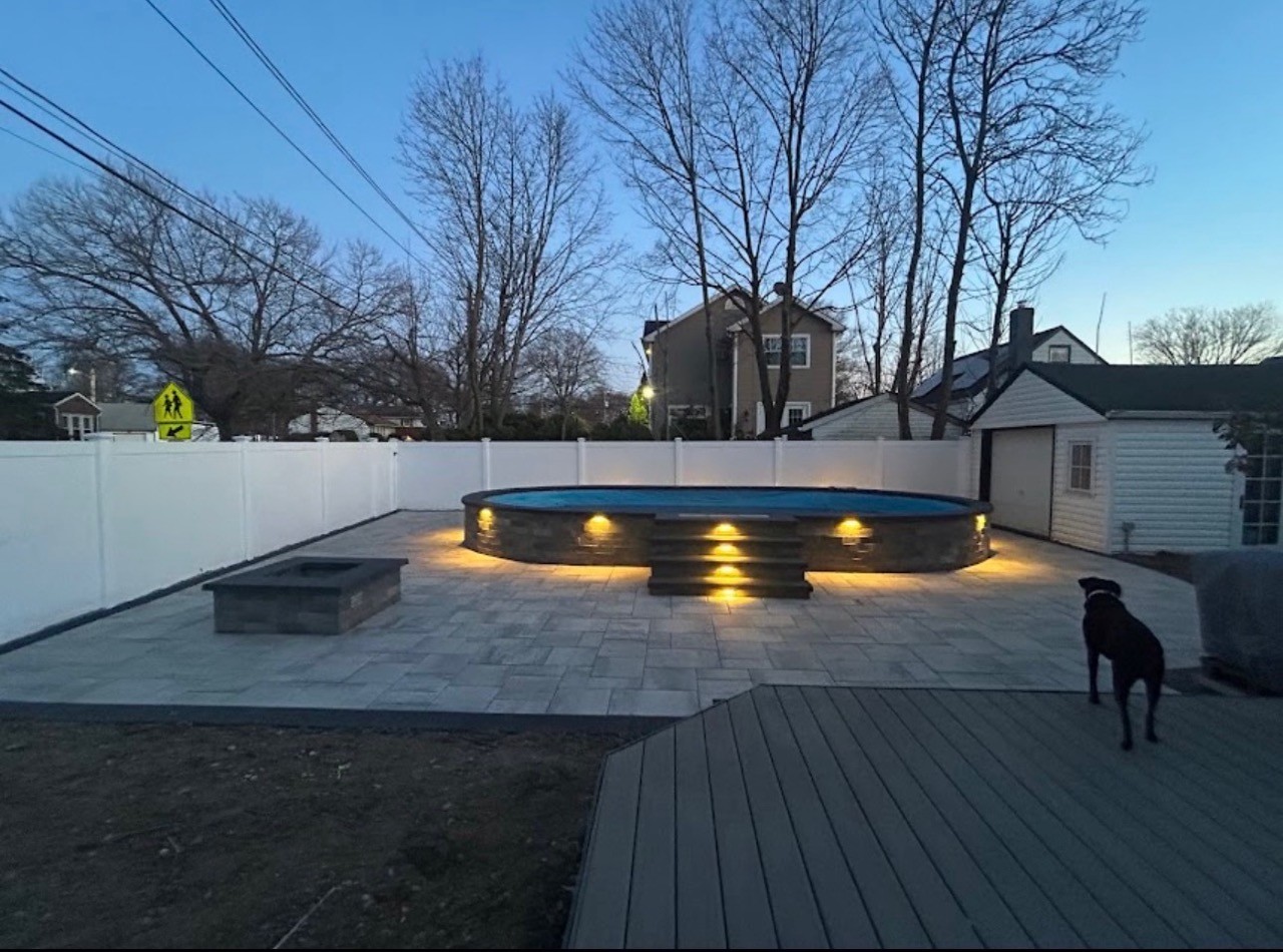 Paver patio with fire pit at night by CMC Masonry