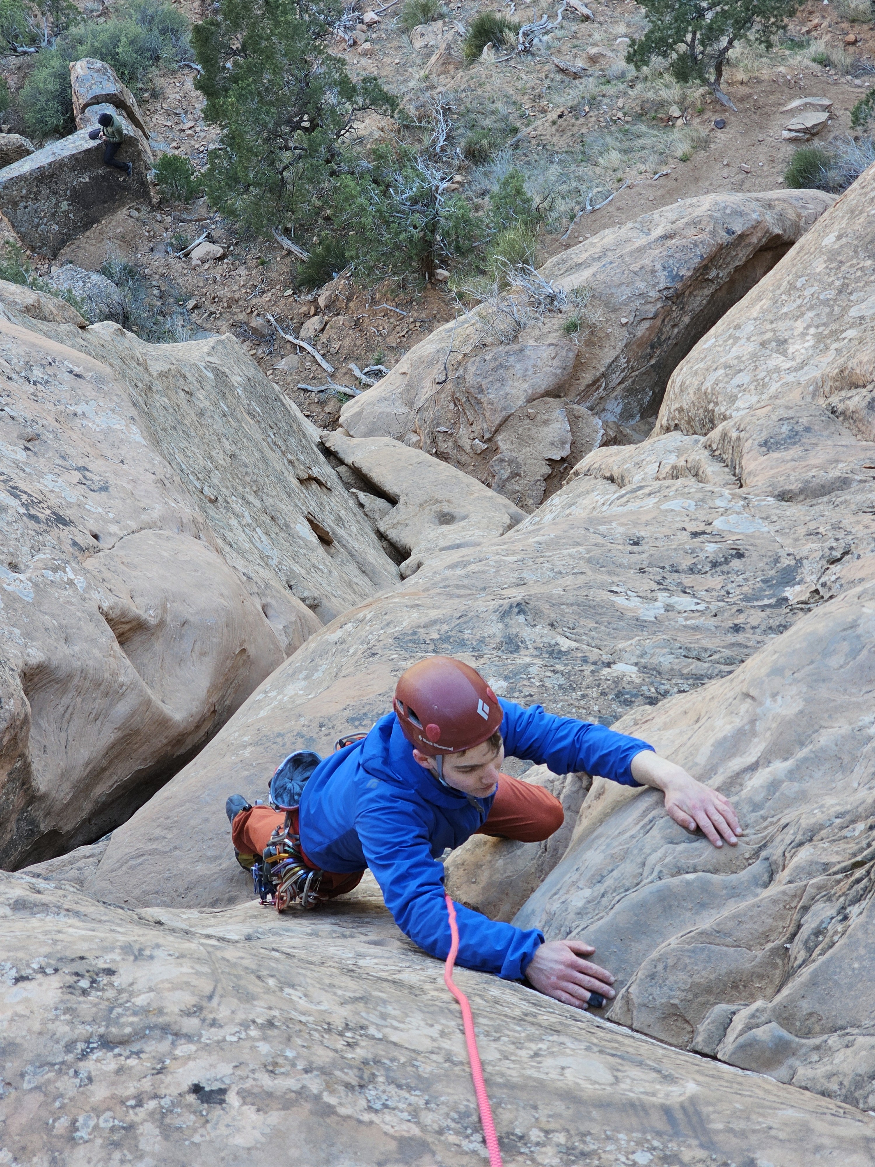Climber in a jacket comes up a shady face