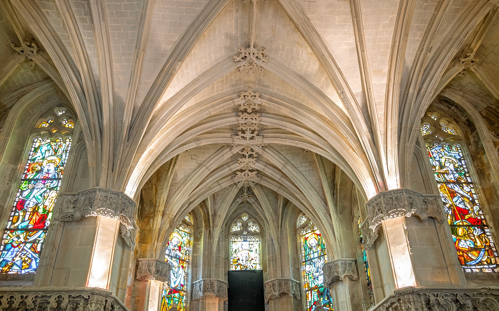 Royal Amboise Castle chapel interior with stained glass windows and vaulted ceiling.