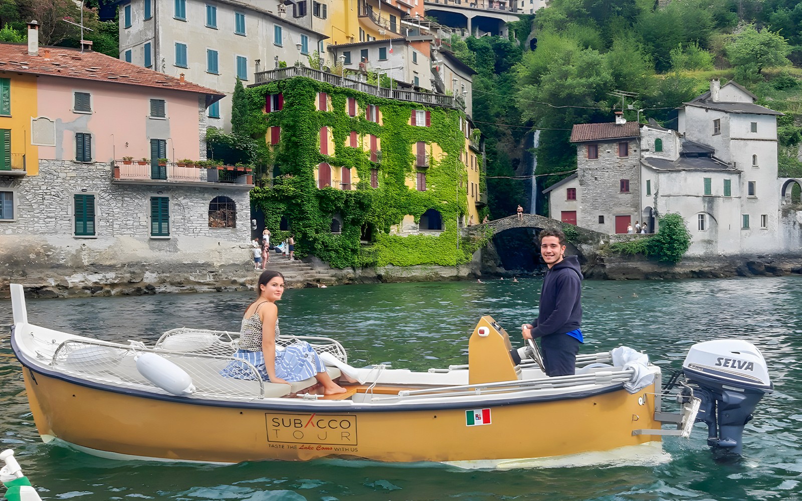 Boat rental on Lake Como with colorful lakeside buildings in the background.