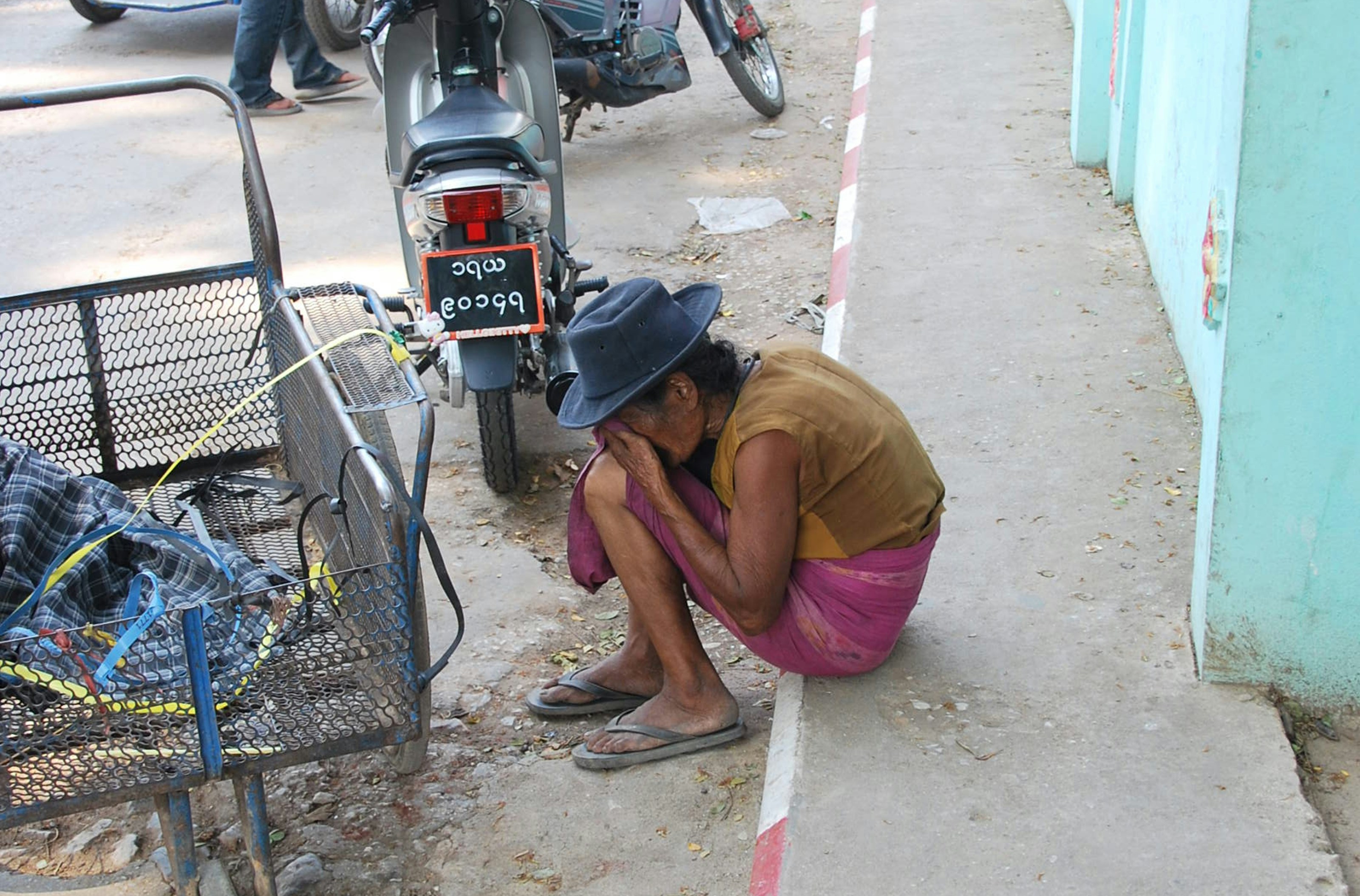 man in brown shirt sitting on gray pavement