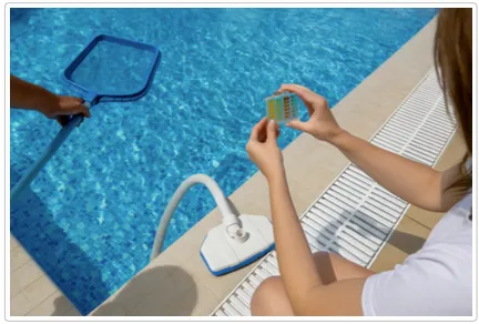 Person checking pool water chemistry with a test block while another person uses a leaf skimmer nearby.
