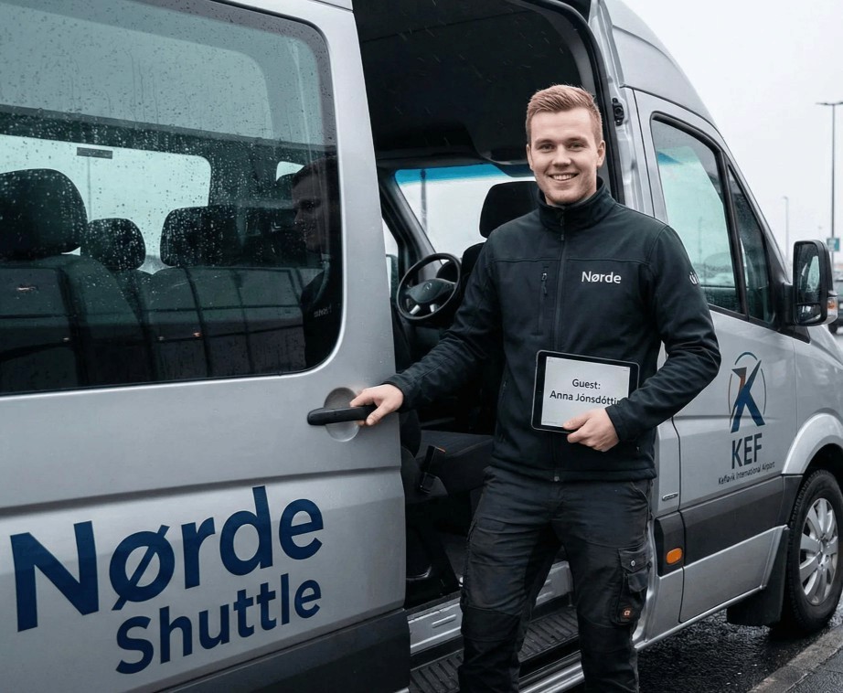 Man holding a tablet standing by the open door of a grey van.