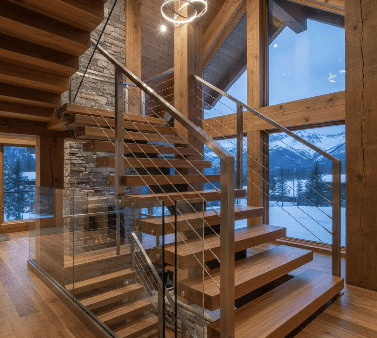 Hybrid staircase design combining glass panels with horizontal stainless steel cable sections.
