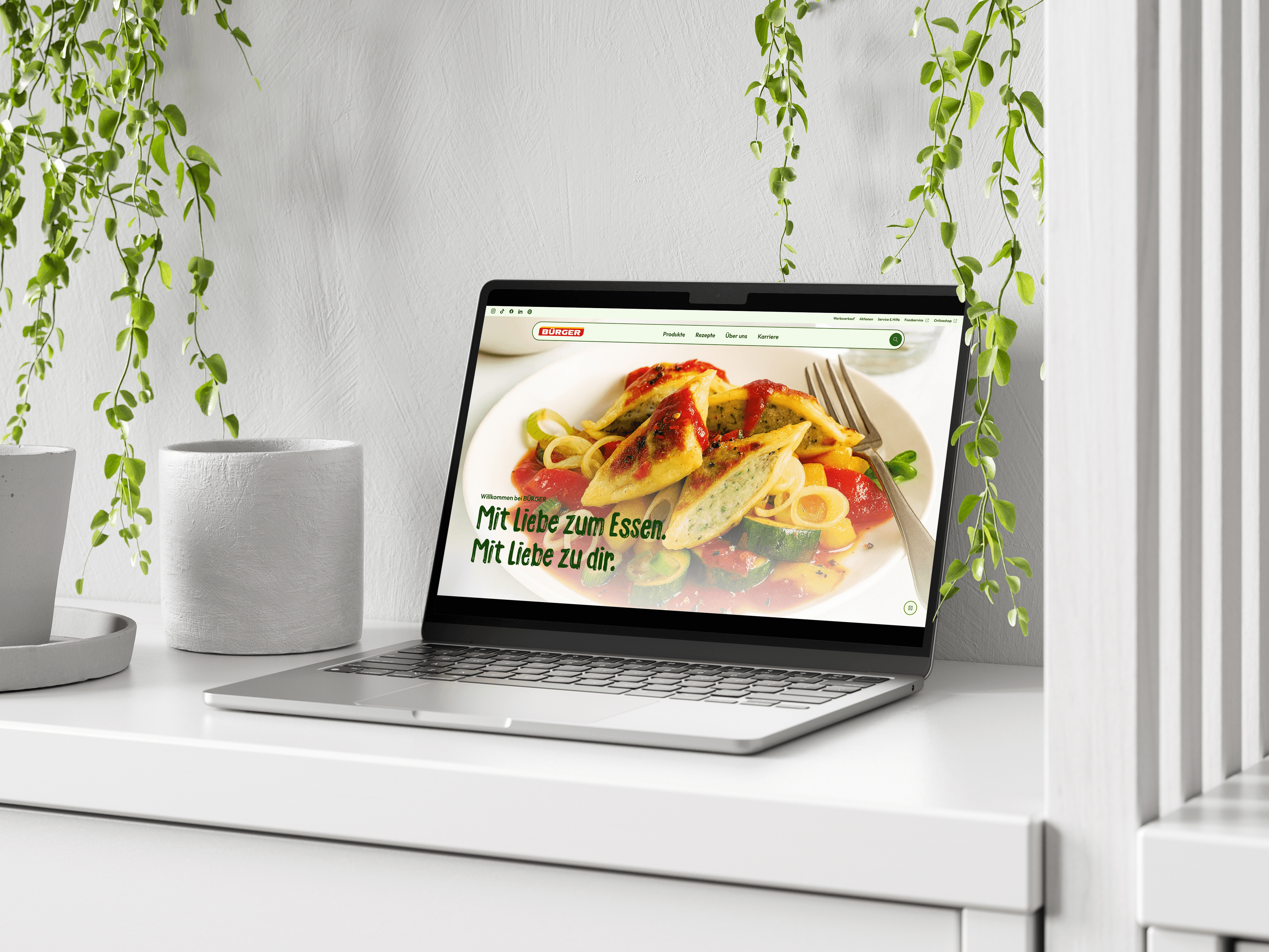 Laptop mockup displaying a bright recipe website with food photography on a dark background, presenting a responsive web design project.