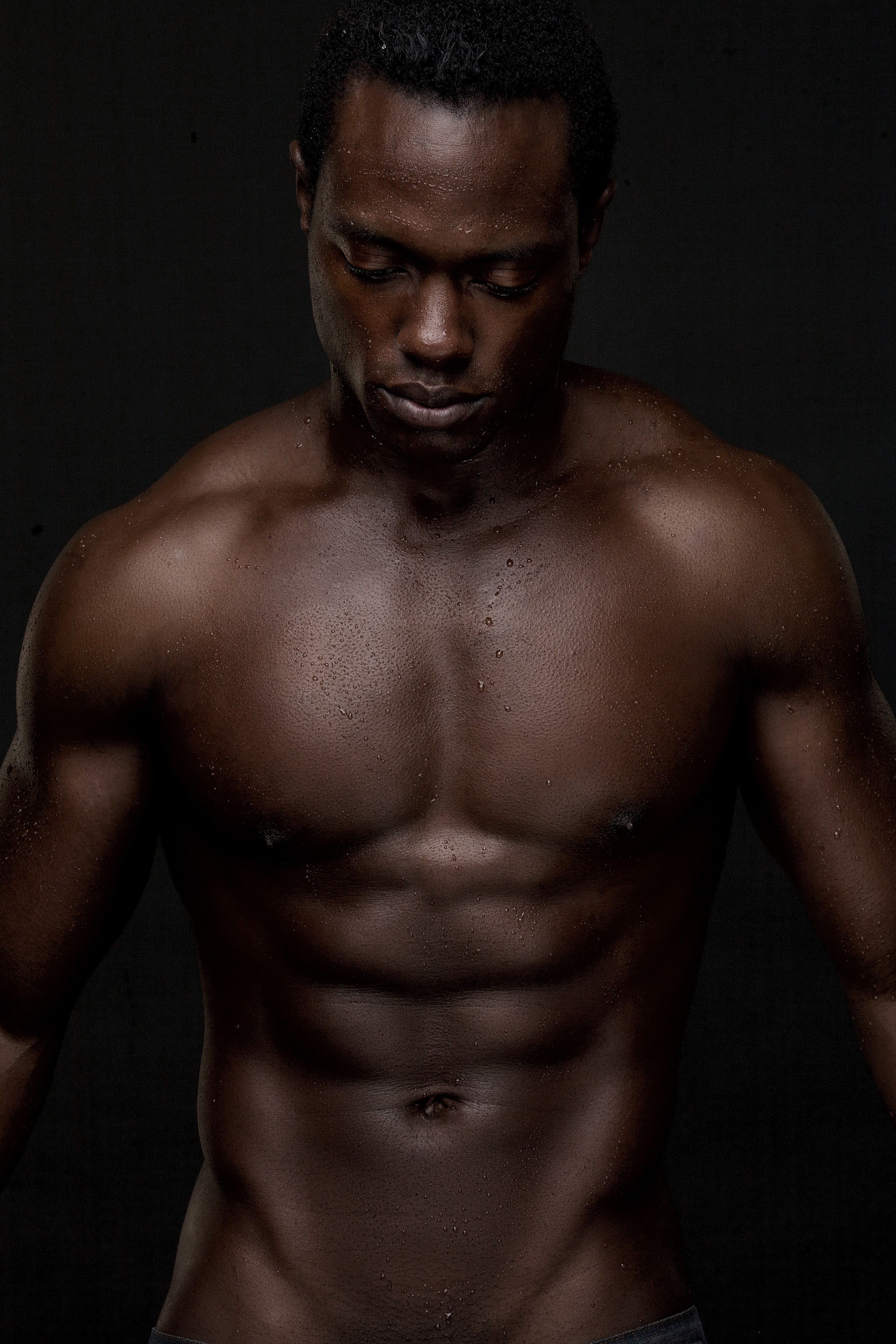 A man posing on a dark backround topless