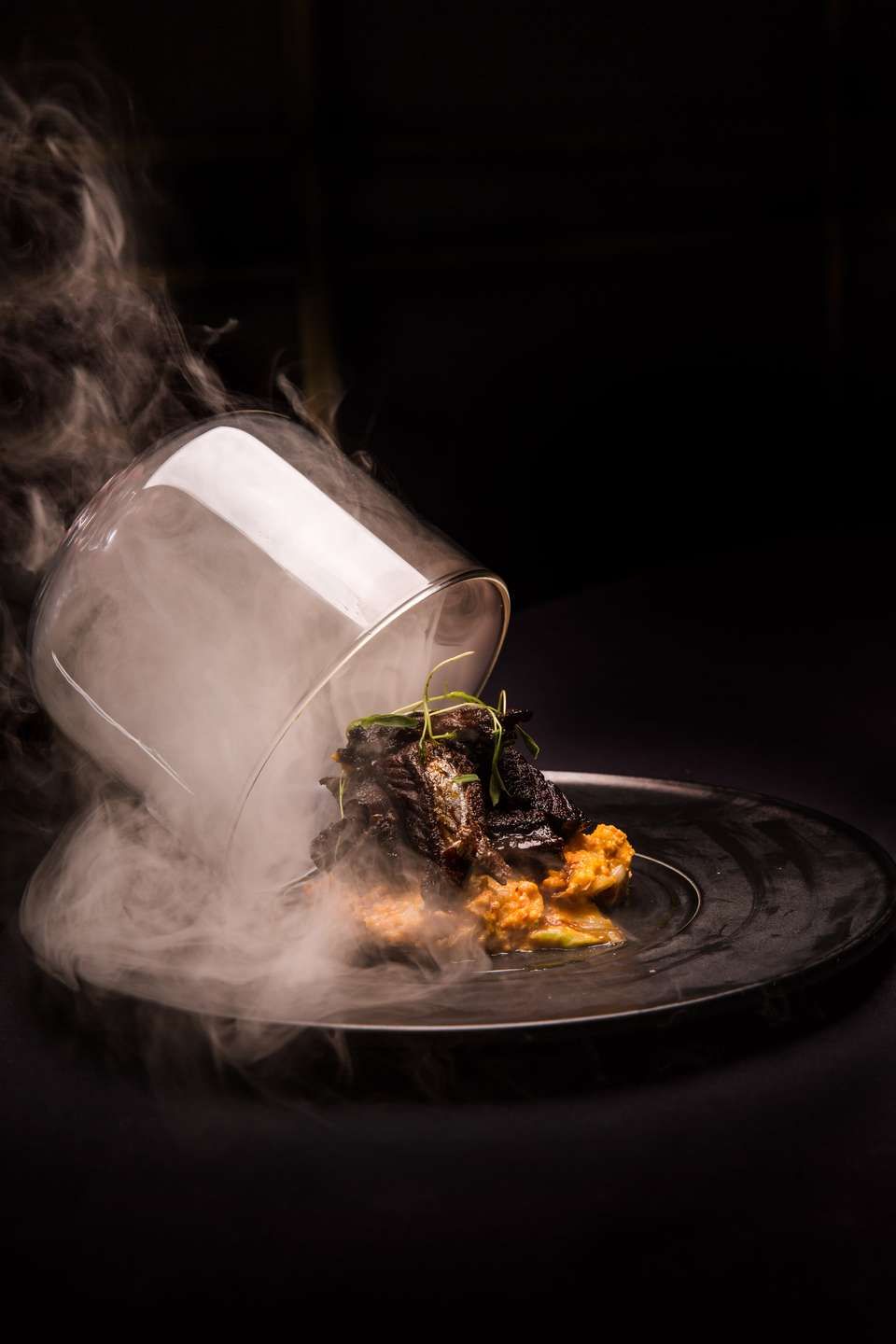 Michelin style Indian dish unveiled from a smoke filled cloche, showcasing modern technique and elevated presentation that reflects the refinement of Indian fine dining.