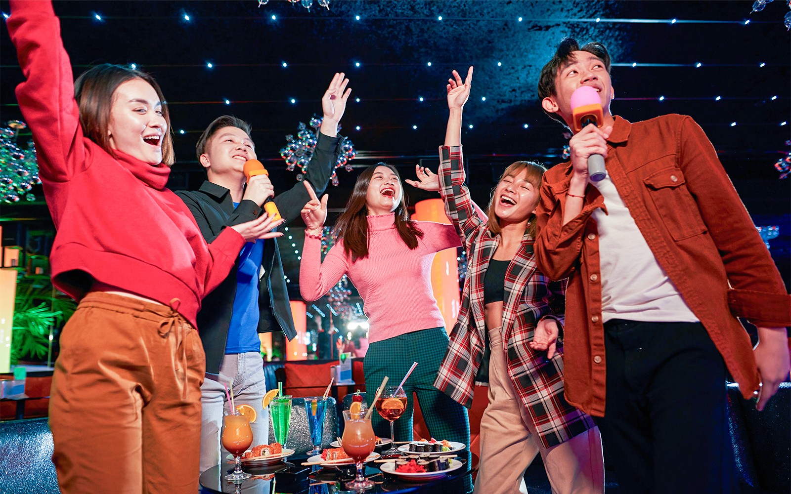 Group enjoying karaoke and drinks at a vibrant indoor venue in Singapore.