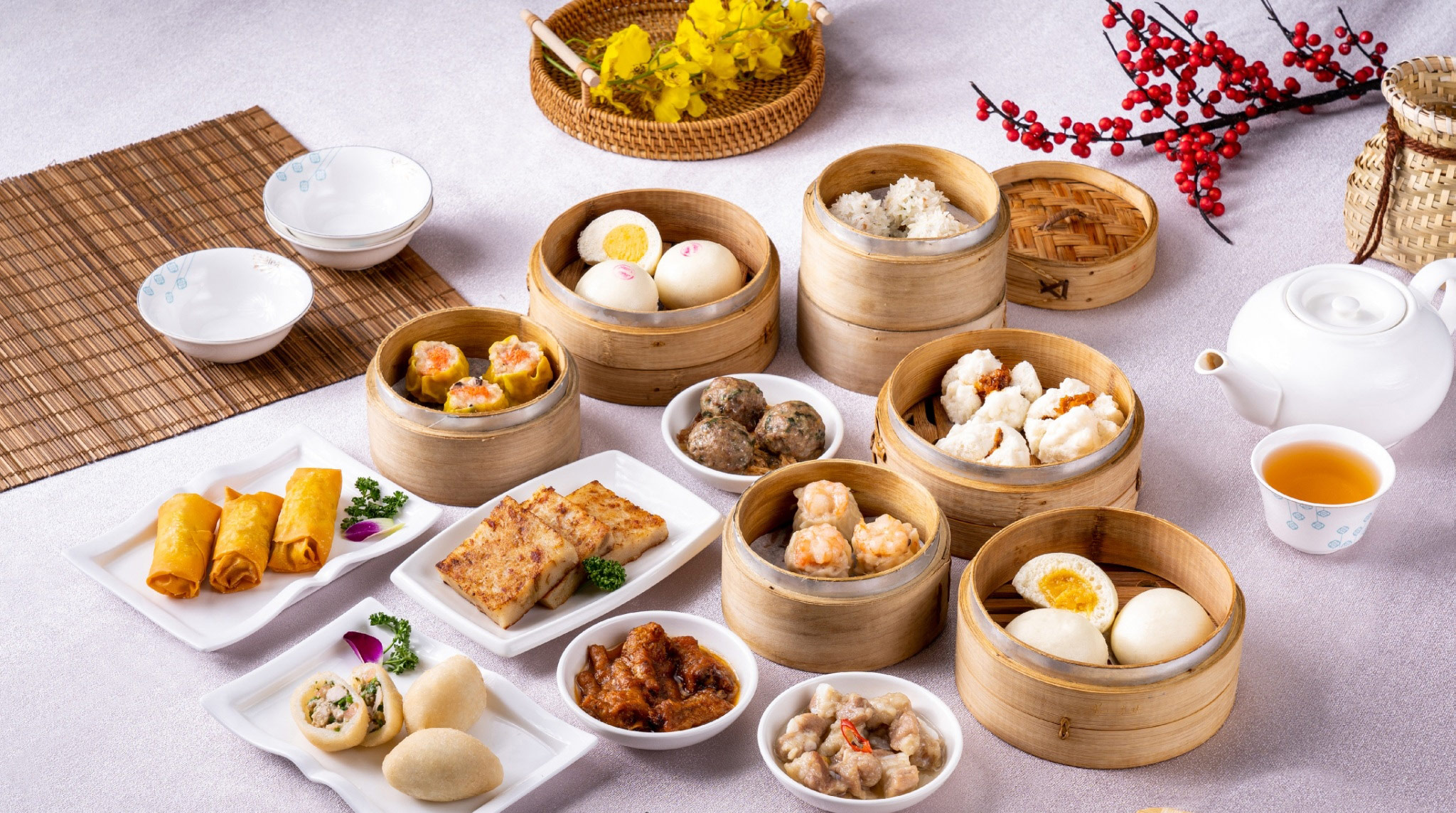 An array of freshly made dim sum at Dum Sum Palace, including Siu Mai, Har Gow, steamed pork ribs, and BBQ buns, served on a traditional bamboo table setting.