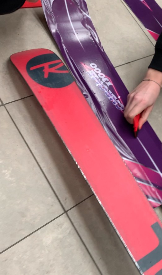Wrapping the skis: a red Rossignol next to a topsheet already covered in purple and pink