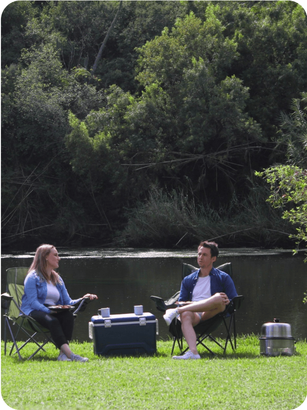 Una pareja disfrutando de un camping, a su lado la parrilla COBB Premier