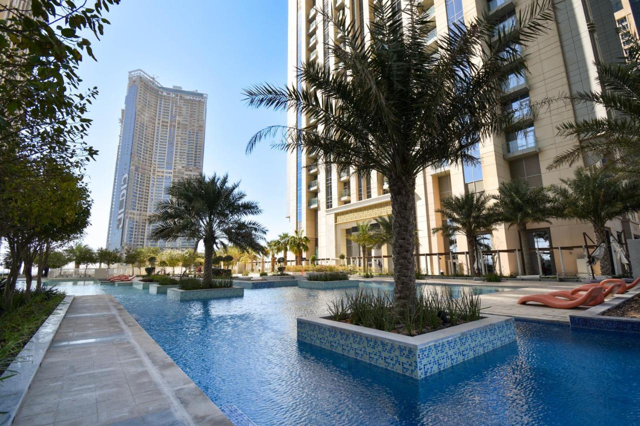 Aerial shot of a swimming pool flanked by palm trees, with Noora Tower prominently in view.