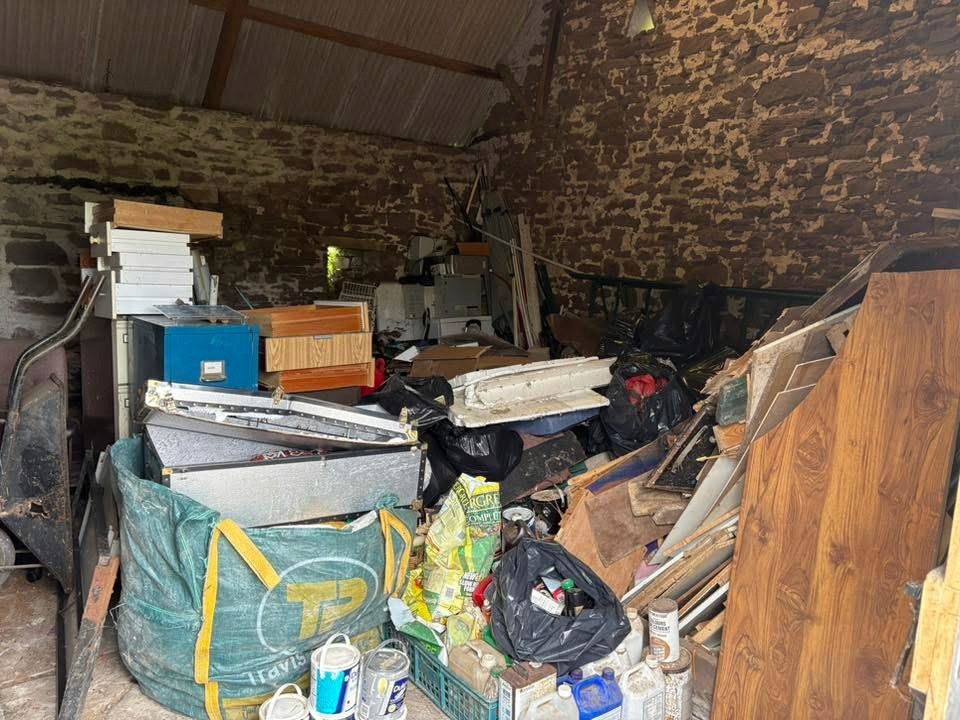 Cluttered outbuilding before a waste clearance