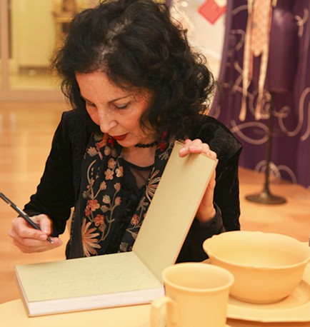 an older woman is signing a book