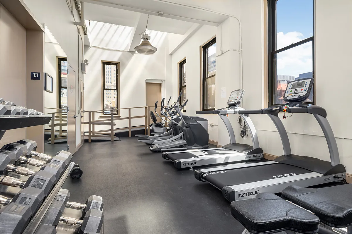 A gym room featuring several treadmills and a large window allowing natural light to enter the space.