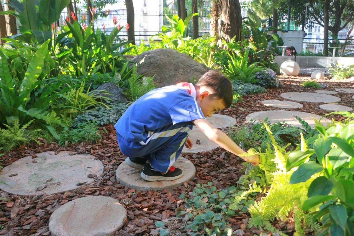 小朋友在花園圓形汀步上探索，展示具美感的戶外專業園藝設計與園林景觀工程，打造舒適綠化空間。