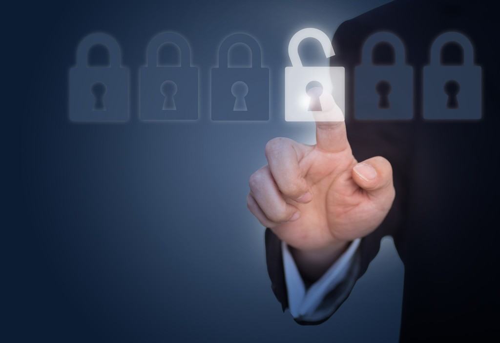 Dedo tocando cadeado digital aberto em painel com múltiplos cadeados fechados, representando vulnerabilidade de segurança e brechas em cibersegurança corporativa - FindUP - Segurança da informação