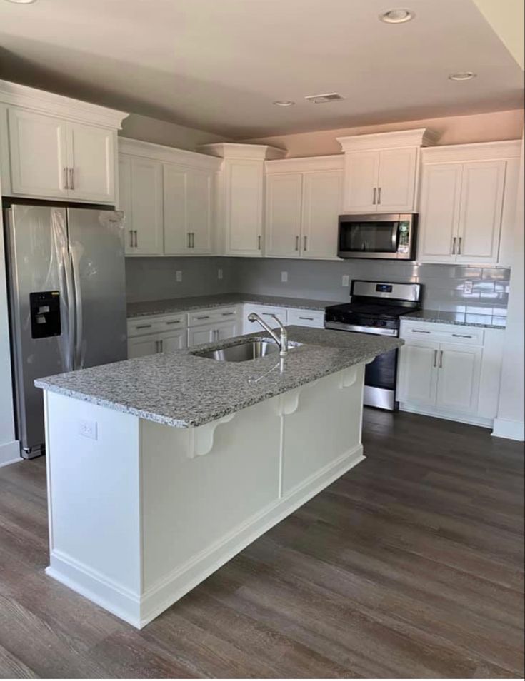 Modern kitchen with a wooden dining table, white chairs, and a hanging light fixture above.