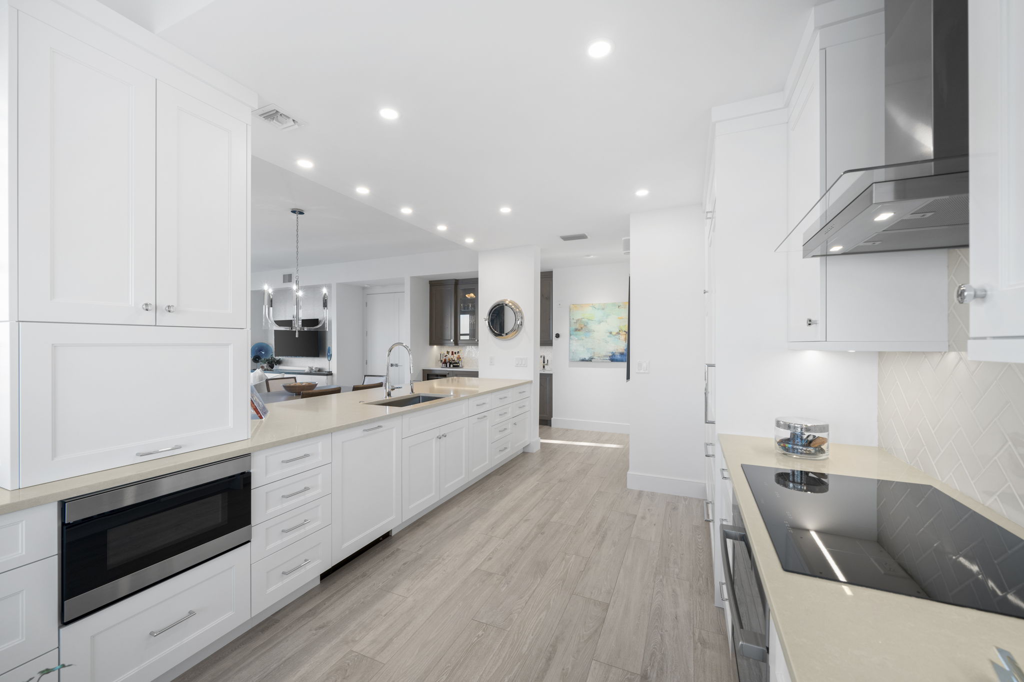 a large kitchen with white counter tops, white cabinets, and a light wood floor