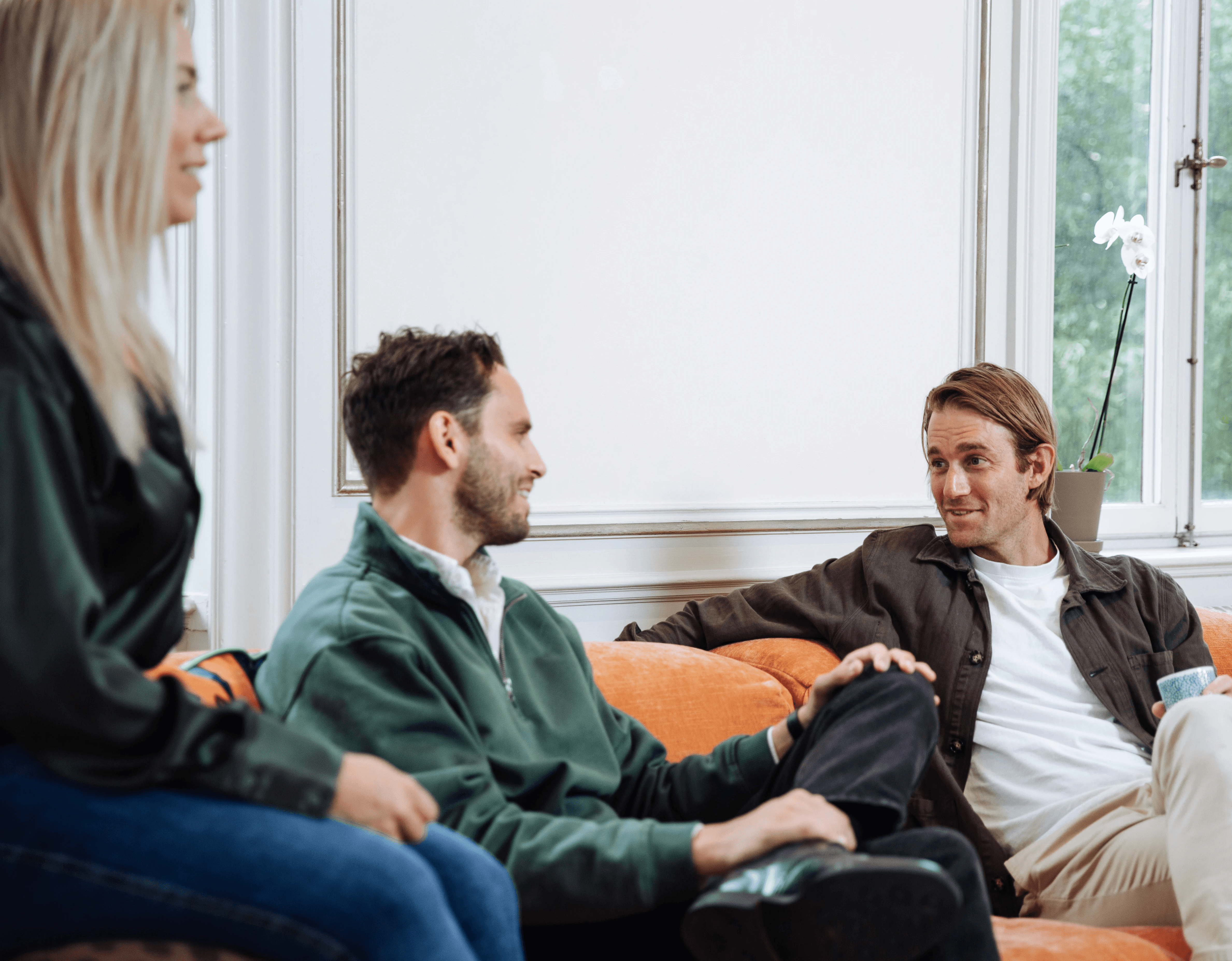 a man and woman sitting on a couch looking at a laptop