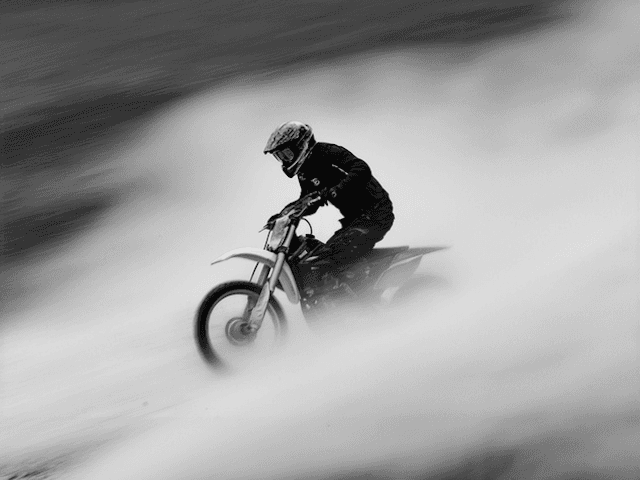 High-speed motocross motion blur photography featuring a motorcyclist speeding through trails with heavy smoke