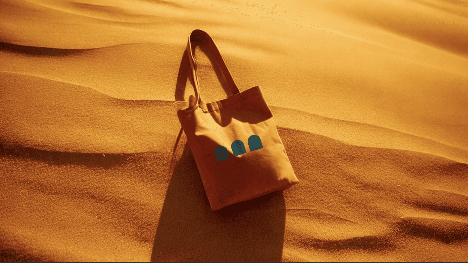 Un sac en toile posé sur les dunes de sable, arborant le logo de "THEVESTINE". Cette image, en harmonie avec les tons de sable, transmet l'idée de simplicité et de fonctionnalité dans un design intemporel.