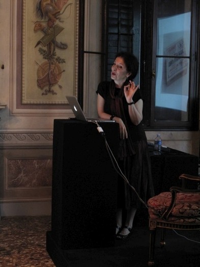 A photo of a woman sitting at a laptop in a room.