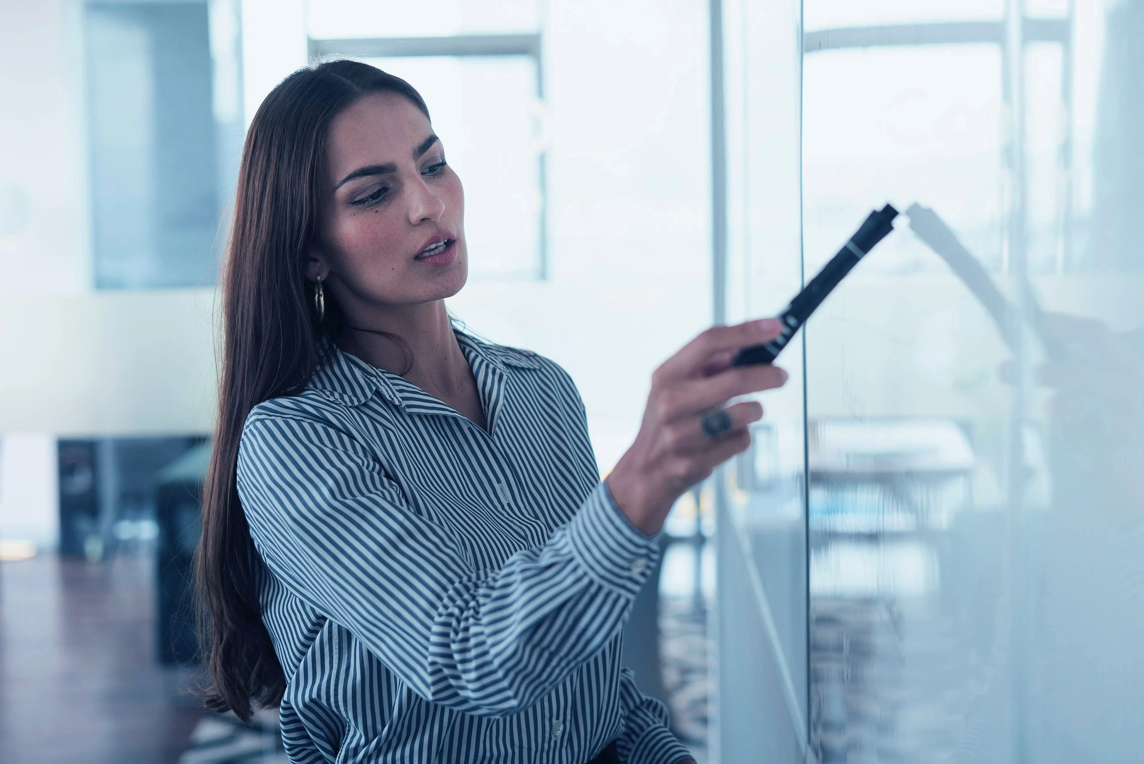 Mujer apuntando a una pizarra con un marcador.