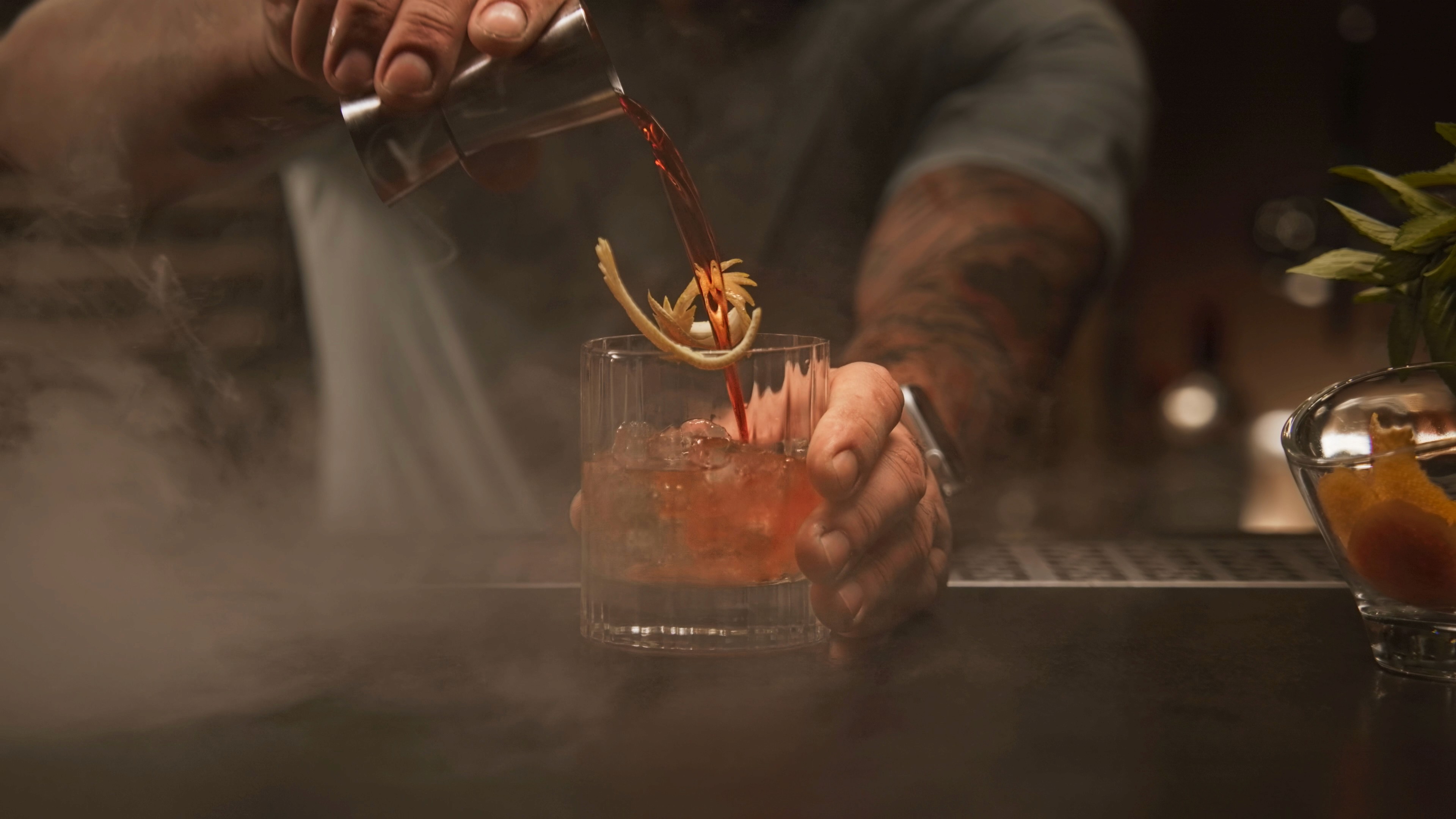 A barman is serving a cocktail in a nice glass