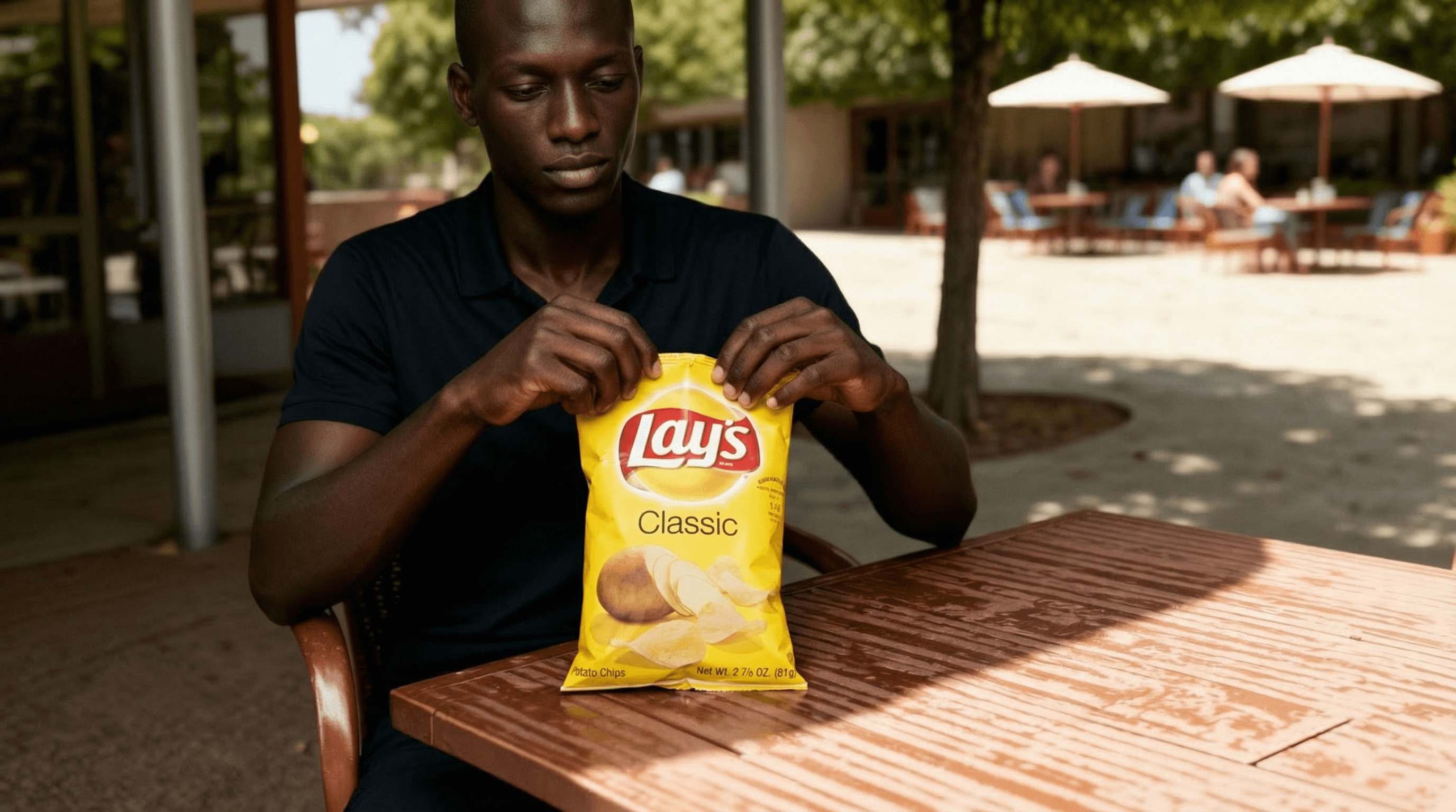 KI-generiertes männliches Model öffnet eine gelbe Lay’s Classic Chips Tüte an einem sonnigen Outdoor-Tisch – hochwertiges Snack- und FMCG-Werbemotiv.