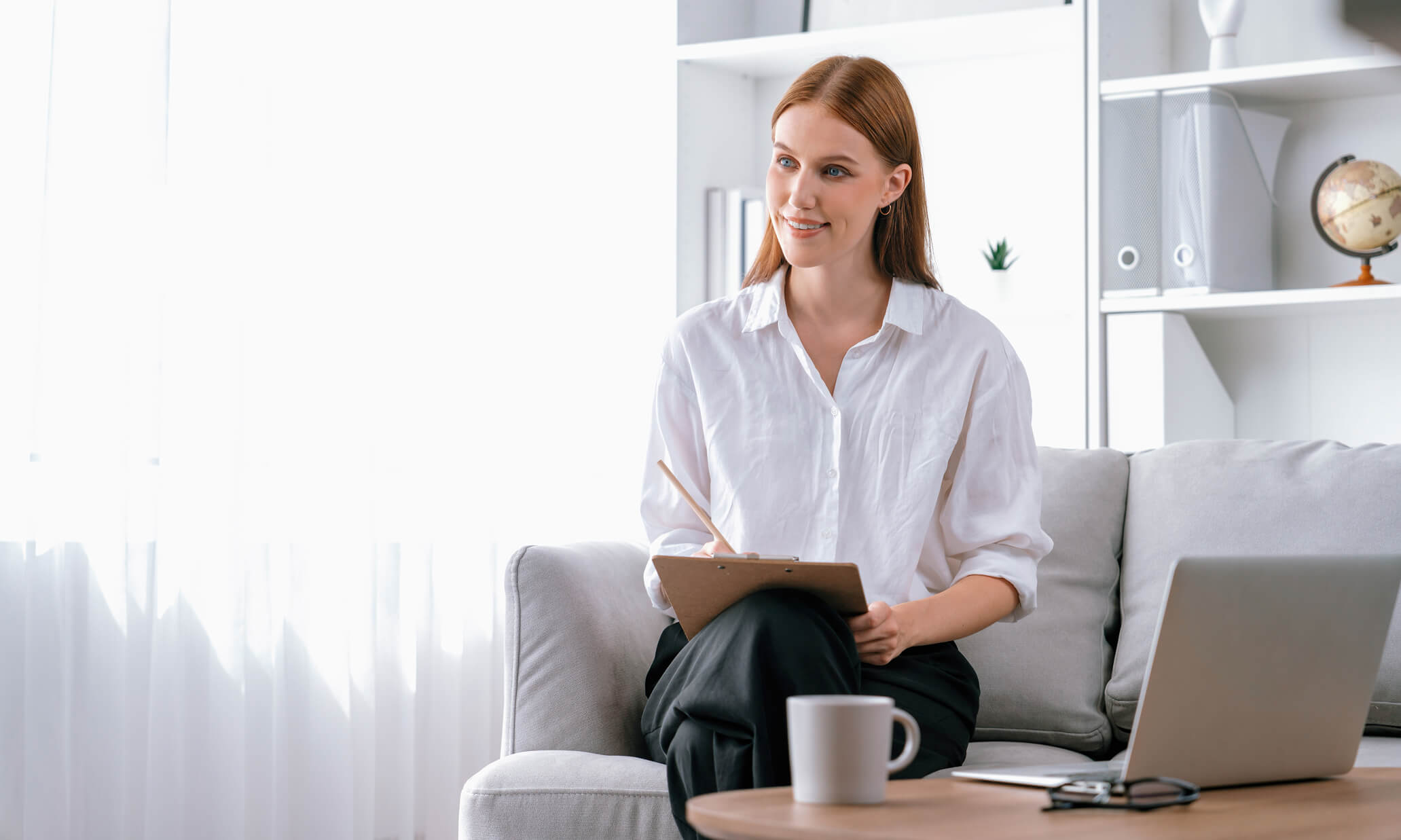 Therapist holding a clipboard while speaking with a client in a bright, modern office