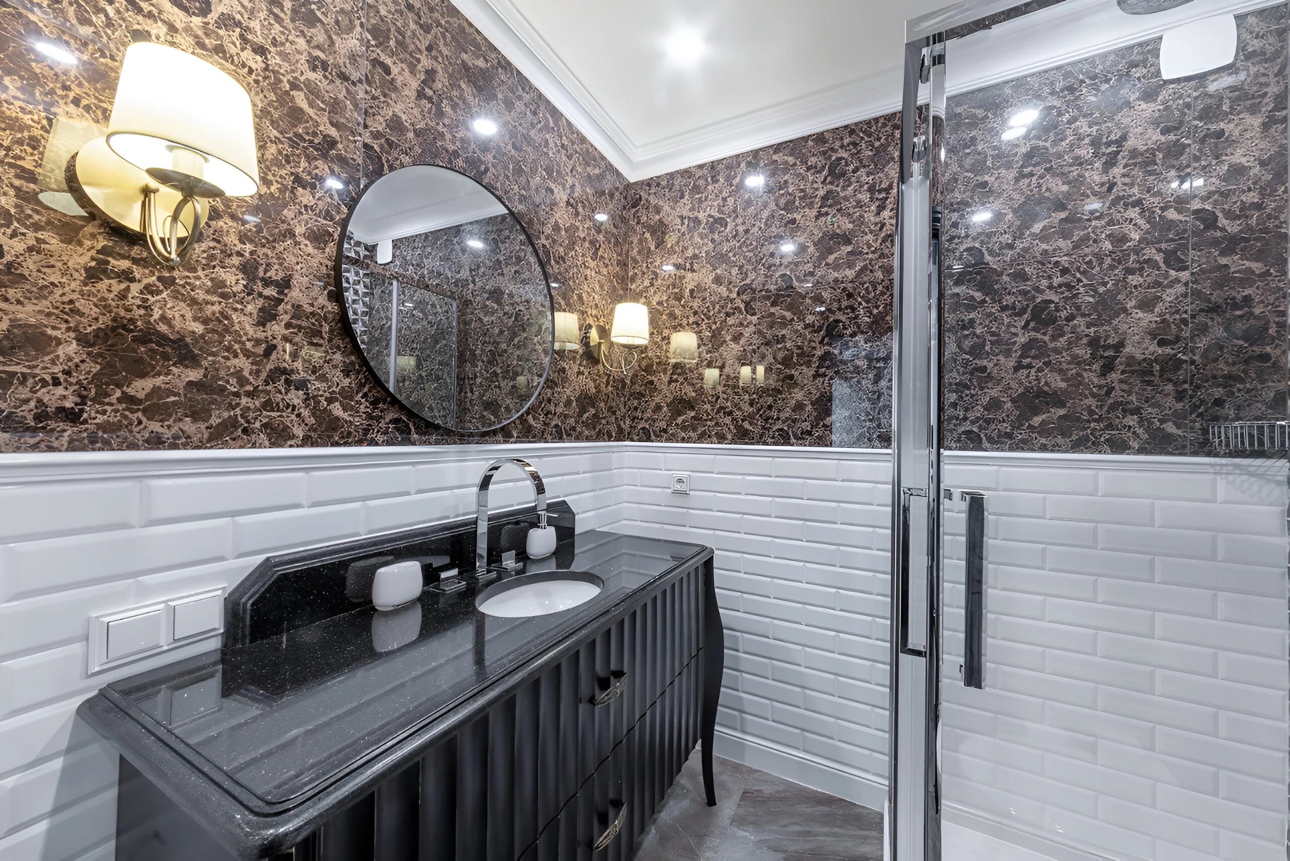 Détail d'une salle de bain de style classique avec vasque sur meuble noir, luminaire décoratif et finitions raffinées.
