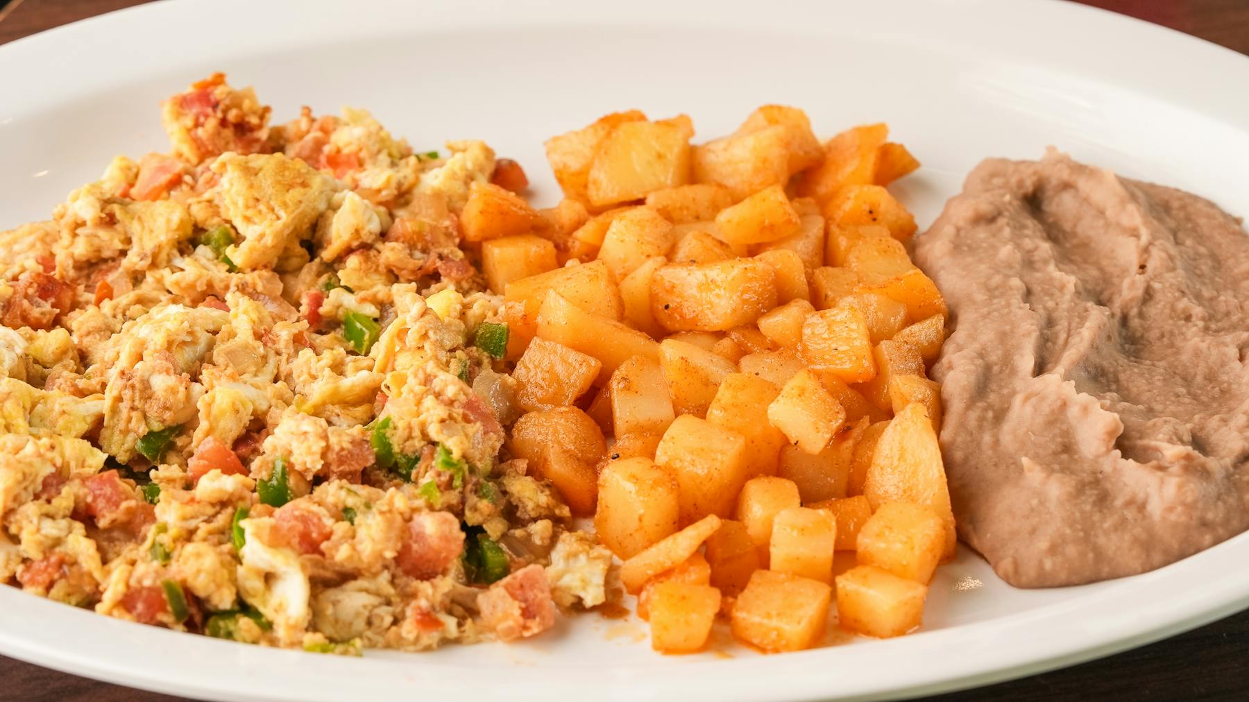 HUEVOS MEXICANA Two fluffy scrambled eggs mixed with onions, tomatoes, and a kick of jalapeño. Served alongside seasoned beans and soft corn tortillas.