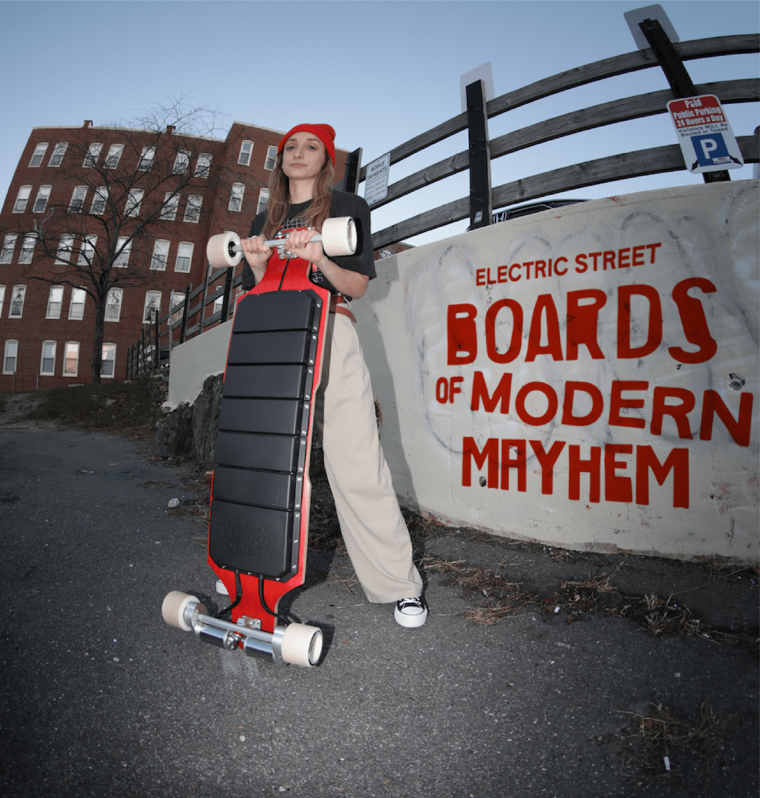 Person in red beanie holding an electric skateboard in an urban setting with bold wall text