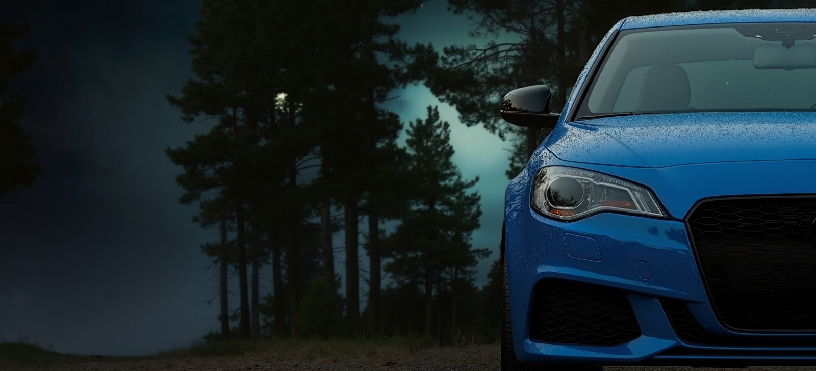 Gros plan sur l'avant d'une voiture bleue mouillée, garée dans une forêt sombre la nuit.