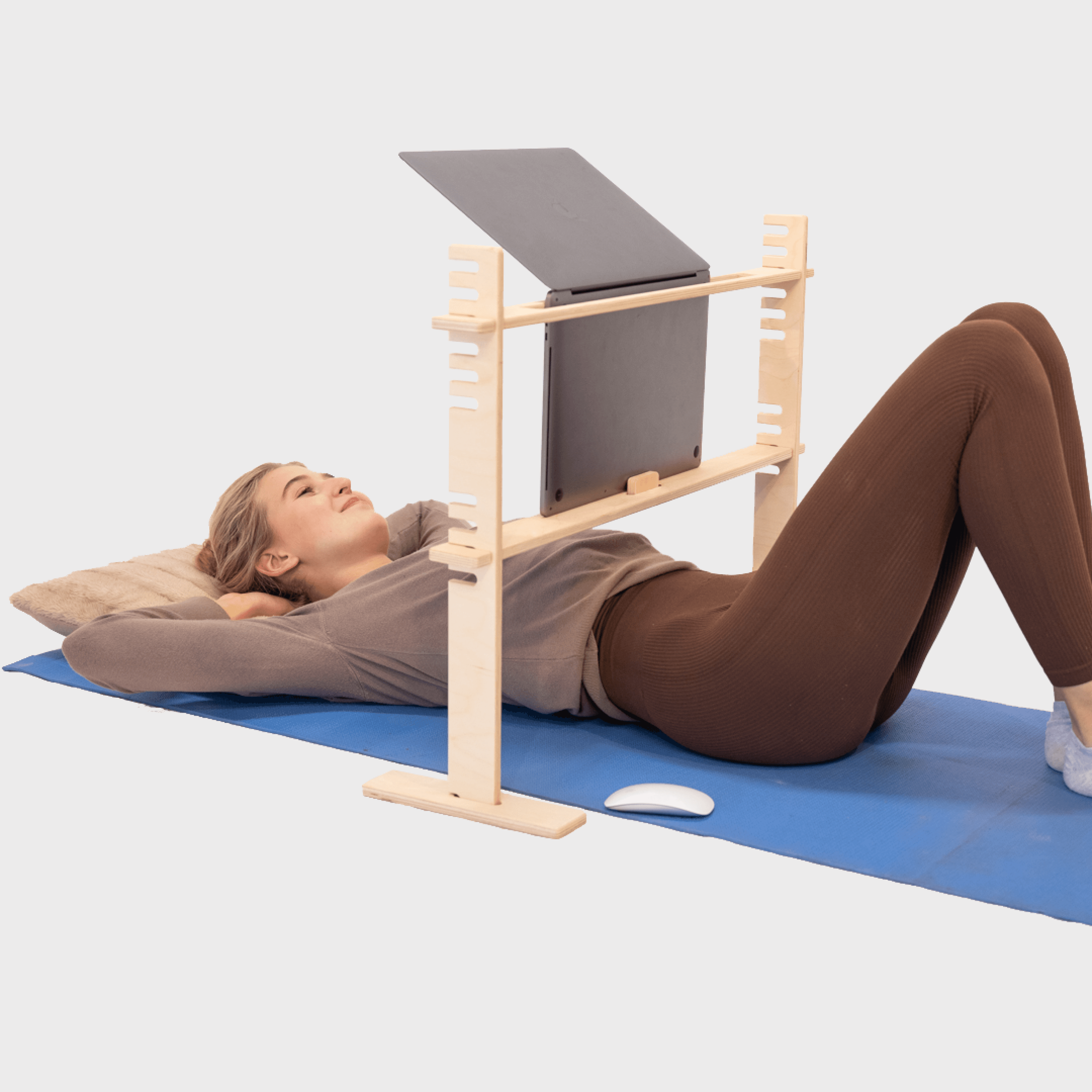 100 Tree Furniture lie down laptop stand being used by a blond girl with a silver Macbook Pro laptop.