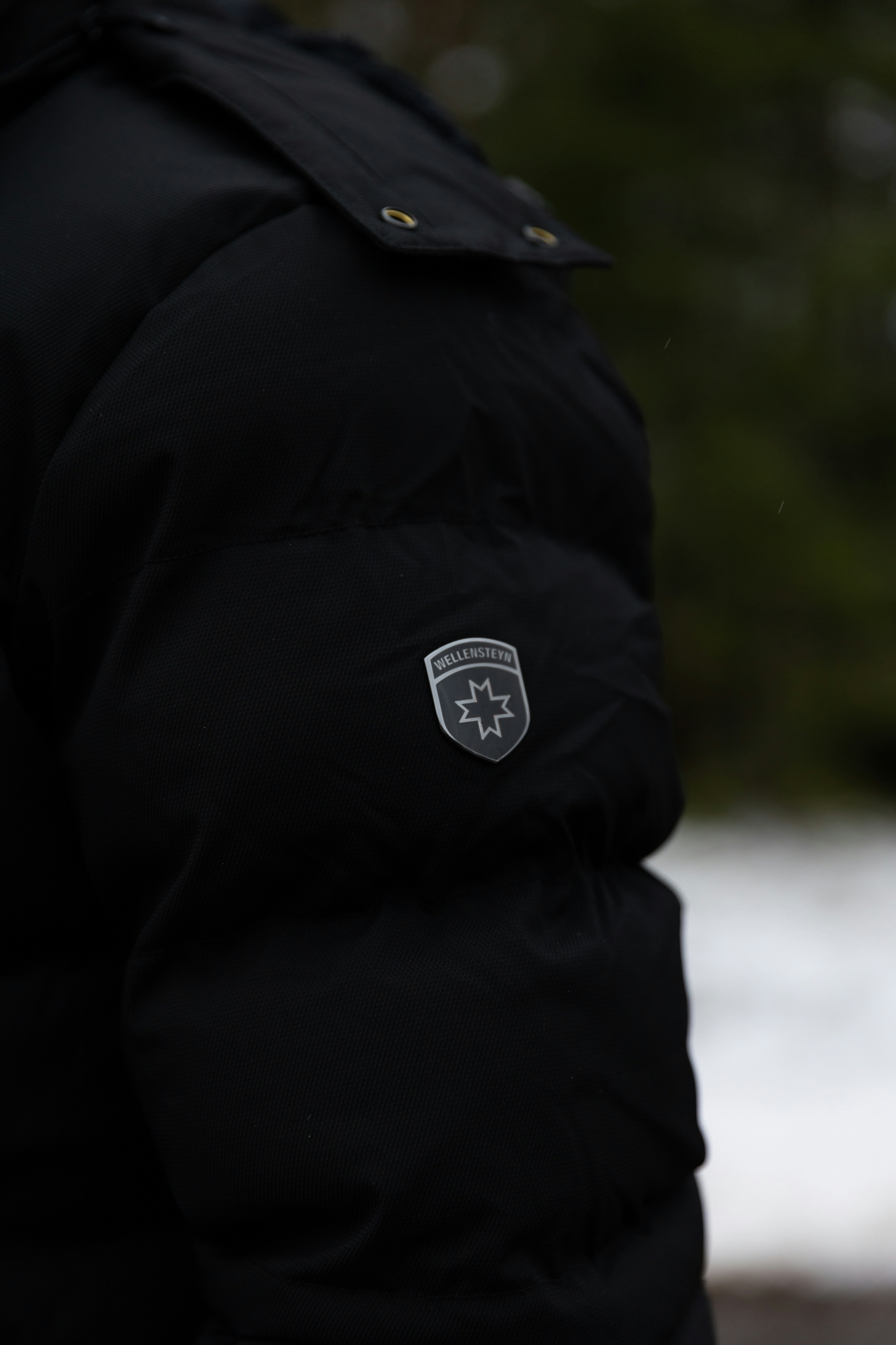 A man in a black jacket with a badge on his pocket
