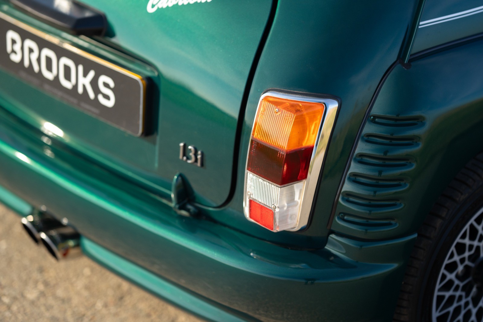 Close-up of the rear corner of a green car, showcasing the taillight and part of the rear bumper.