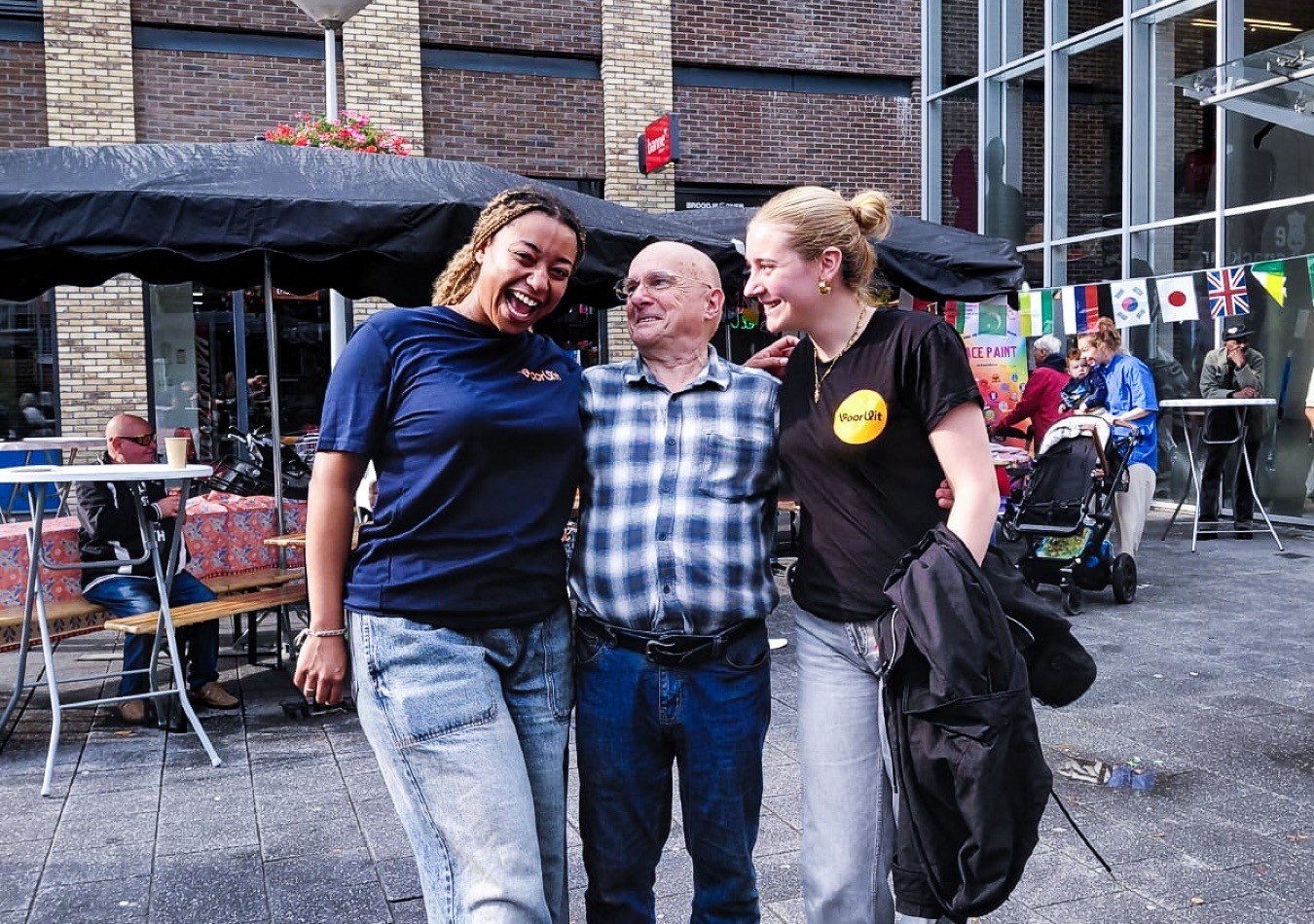 Drie buurtbewoners lachen samen op een plein tijdens een buurtevenement
