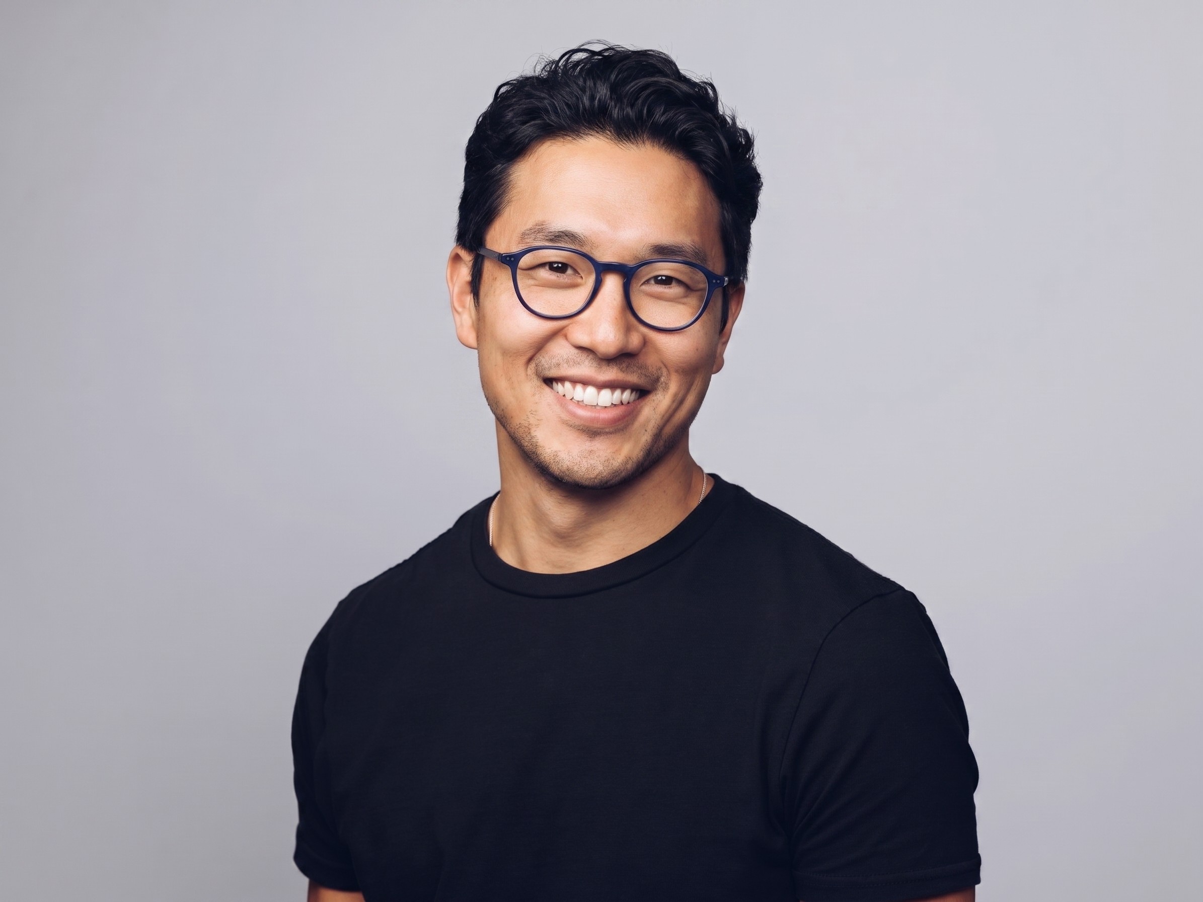 A person smiling and posing with a dark background.