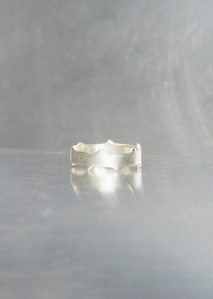 Silver ring on a reflective gray surface with a neutral background